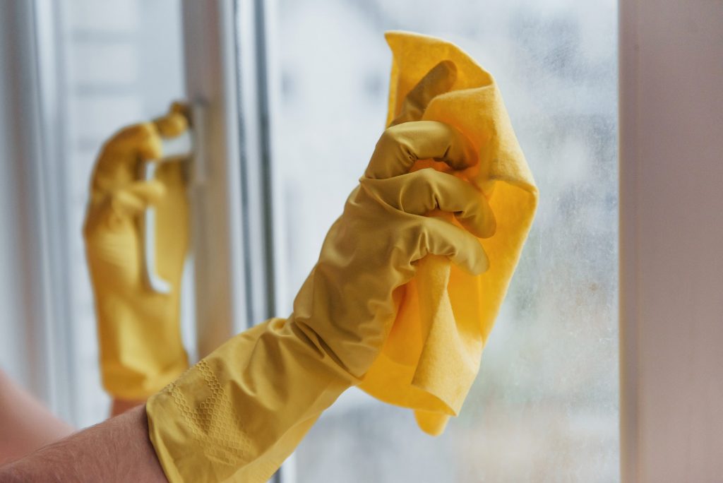 Housewife in yellow uniform cleaning windows. House renovation conception